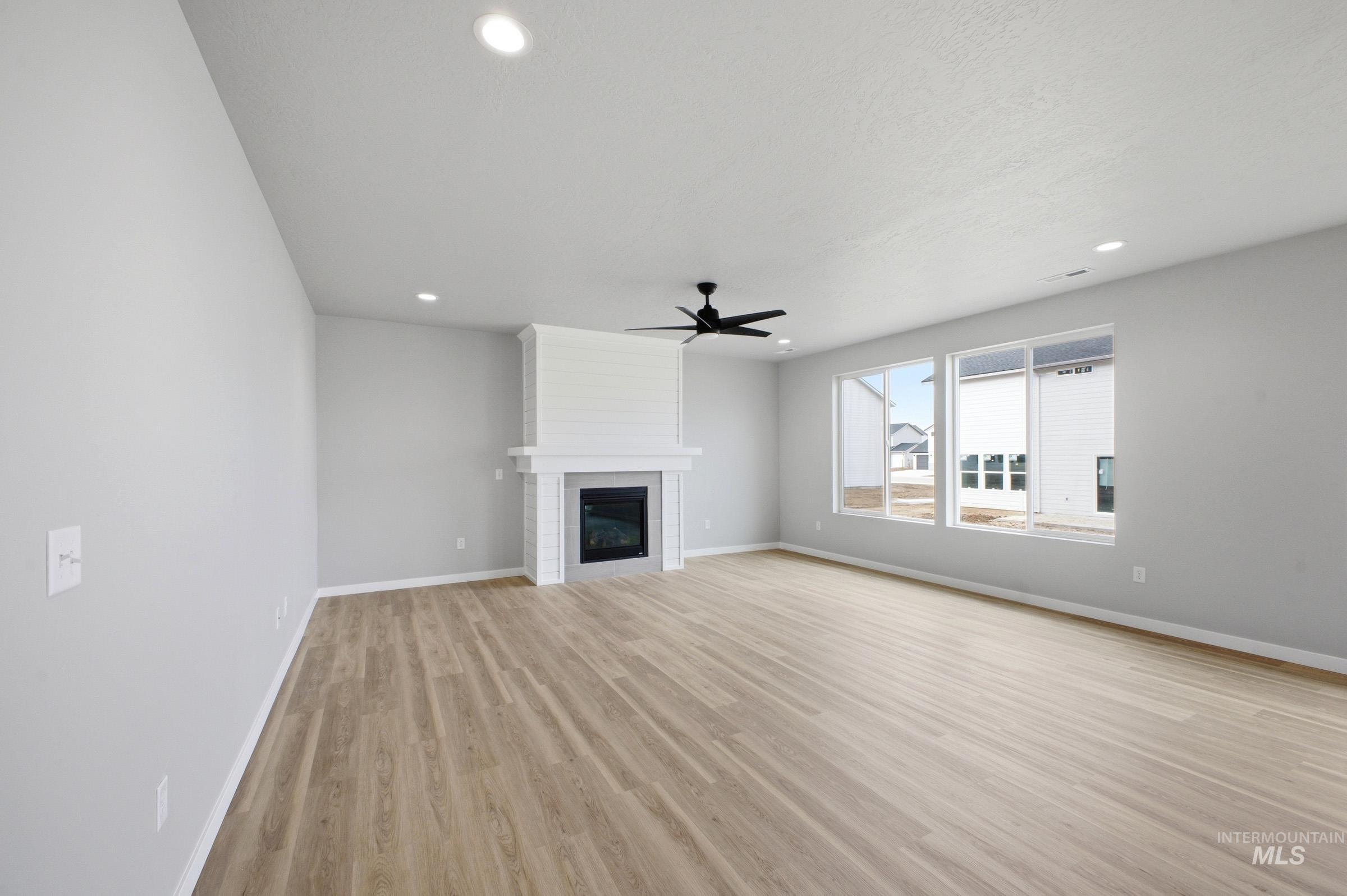 13672 Redway Court Caldwell, ID 83607 - Photo 7 of 34 Unfurnished living room with light wood-type flooring, a fireplace, a ceiling fan, and recessed lighting