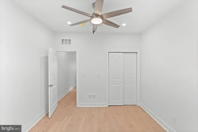 an empty room with closet and a ceiling fan