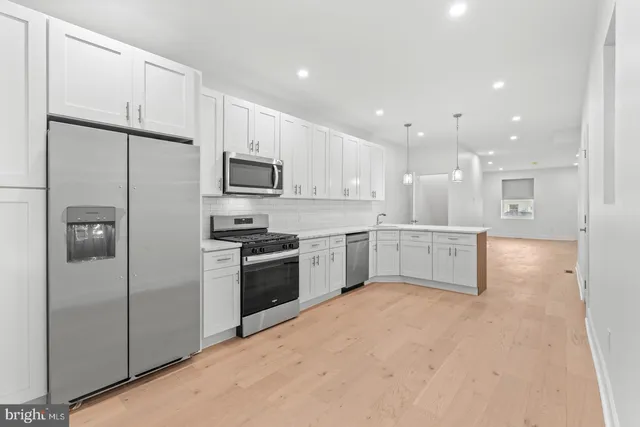 a kitchen with stainless steel appliances kitchen island a white cabinets a sink a refrigerator and a stove