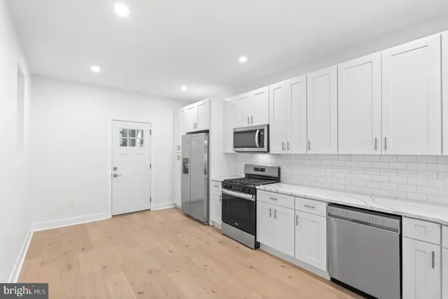 a kitchen with stainless steel appliances a white stove top oven and white cabinets