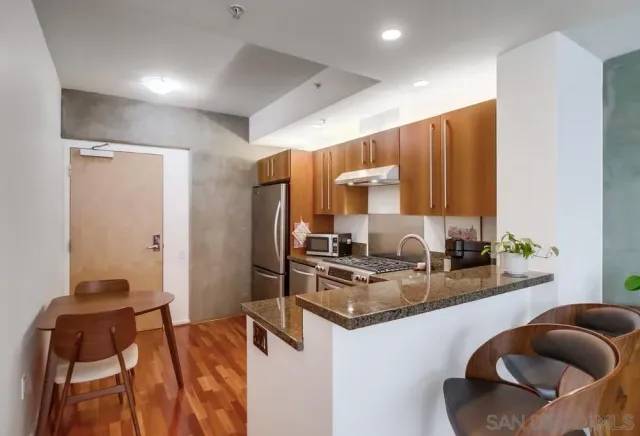 a kitchen with stainless steel appliances granite countertop a couch and a wooden cabinets