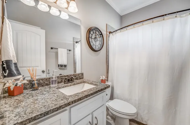 a bathroom with a granite countertop sink mirror vanity and a toilet