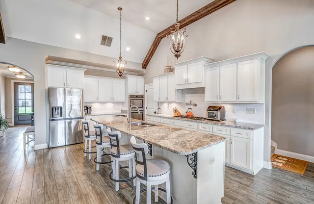 a kitchen with granite countertop a table chairs stainless steel appliances and wooden floor