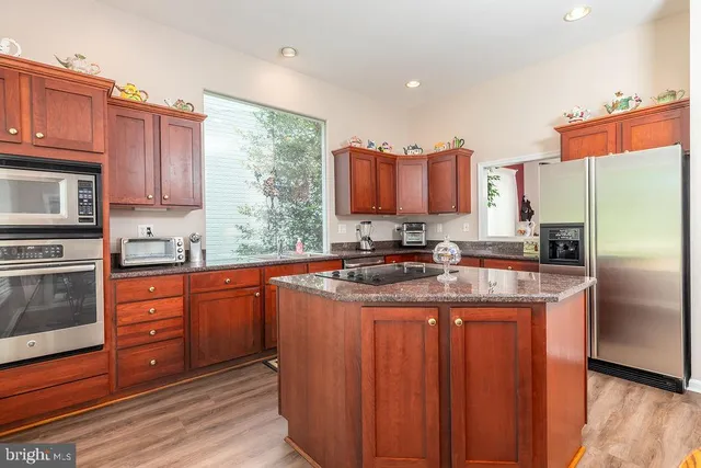 a kitchen with stainless steel appliances granite countertop a stove a sink dishwasher a refrigerator and a microwave oven with wooden cabinets