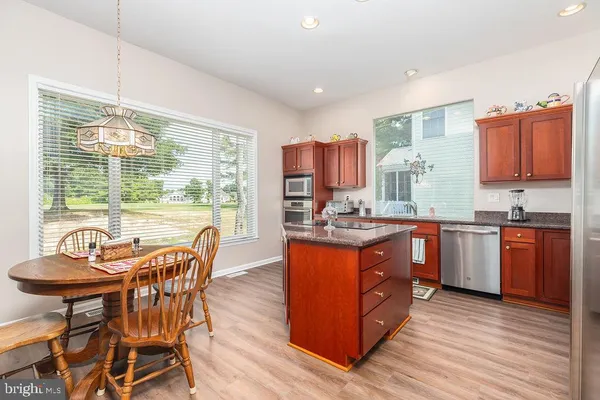 a kitchen with stainless steel appliances granite countertop wooden floors and a view of living room