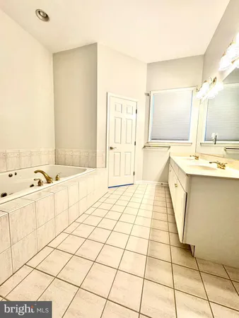 a spacious bathroom with a tub a sink and a mirror
