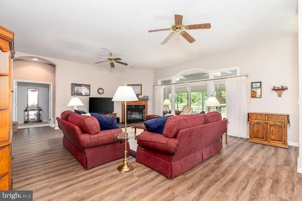 a living room with furniture ceiling fan and a wooden floor