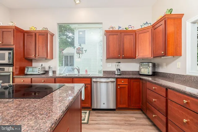 a large kitchen with kitchen island granite countertop wooden cabinets a granite counter and a sink