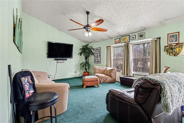a living room with furniture a ceiling fan and a flat screen tv