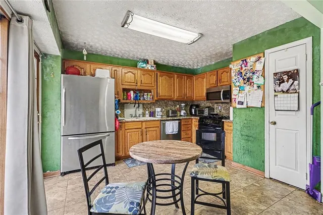 a kitchen with stainless steel appliances granite countertop a refrigerator and a dining table