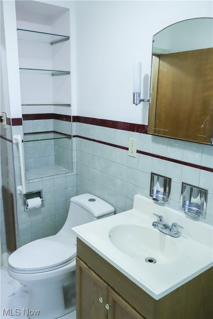 5880 Jaycox Road North Ridgeville, OH 44039 - Photo 11 of 21 Bathroom featuring backsplash, toilet, vanity, and tile walls