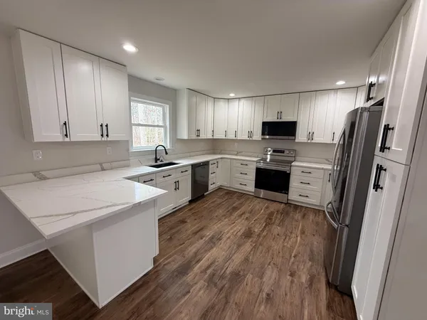a kitchen with granite countertop a refrigerator sink and wooden cabinets