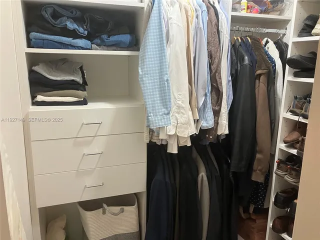 a view of walk in closet with clothes and shoes