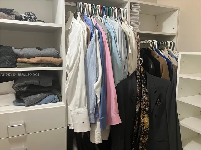 a view of walk in closet with clothes and shoes