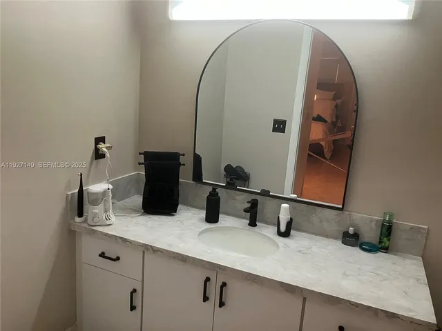a bathroom with a granite countertop sink and a mirror