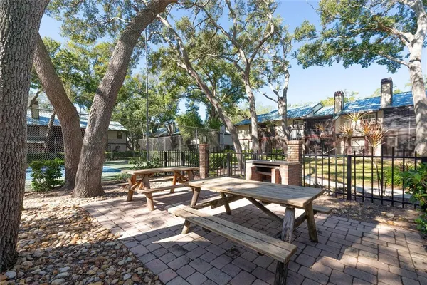 a view of a patio with couches table and chairs under an tree