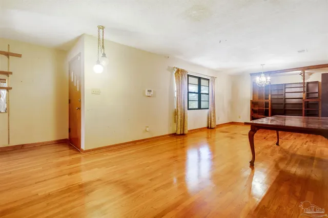 a view of an empty room with window and wooden floor