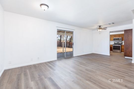 718 Sonja Avenue Ridgecrest, CA 93555 - Photo 8 of 33 an empty room with wooden floor and way to kitchen