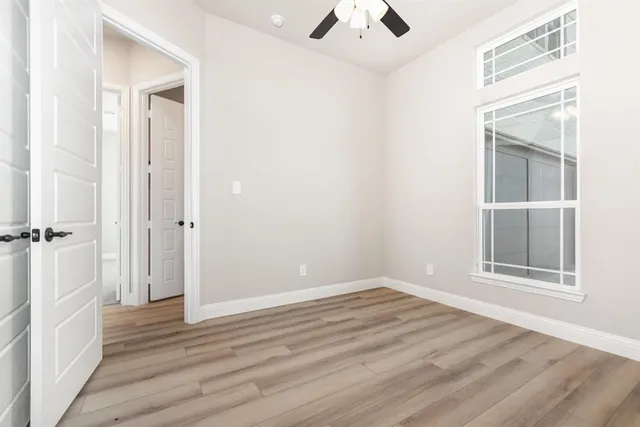 an empty room with wooden floor cabinet and windows