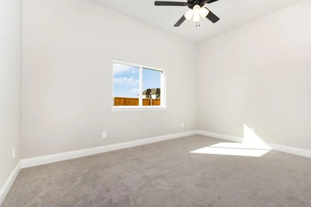 an empty room with a ceiling fan and window