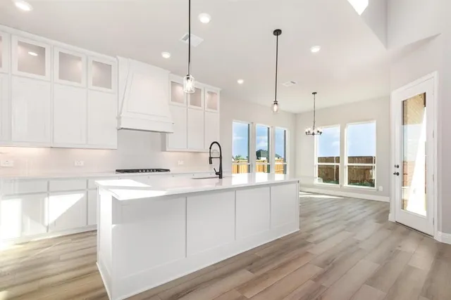 a kitchen with stainless steel appliances granite countertop a sink a stove and a wooden floors