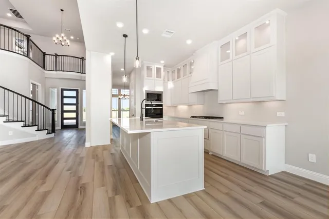 a kitchen with white cabinets appliances wooden floor and a window