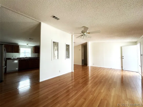 an empty room with wooden floor fan and windows