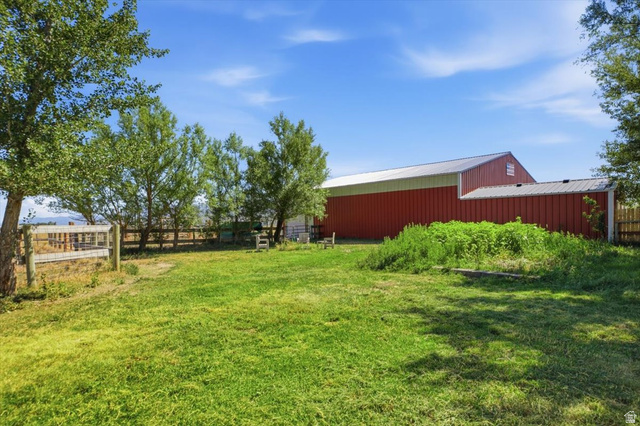1634 West Arimo Road Arimo, ID 83214 - Photo 26 of 89 Expansive grassy area with a red barn structure featuring a metal roof and an attached shed