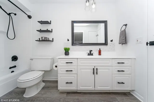 a bathroom with a granite countertop sink mirror vanity and toilet