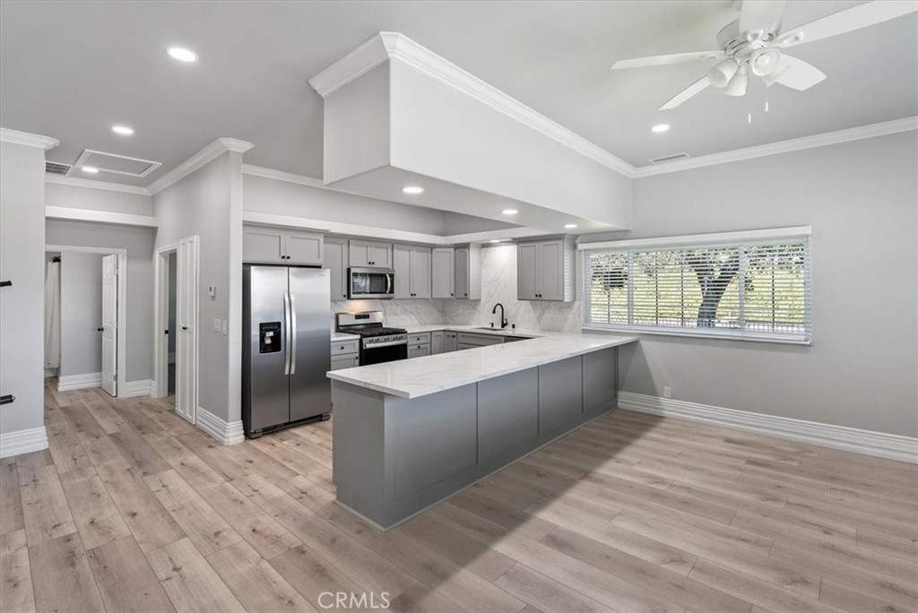 8283 Cross Canyons Road San Miguel, CA 93451 - Photo 63 of 73 a large white kitchen with kitchen island a refrigerator a stove a sink dishwasher and a dining table with wooden floor