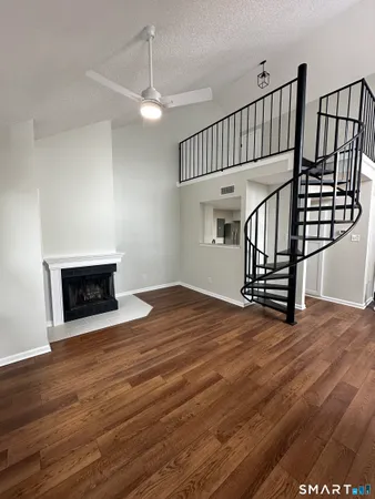 a view of an empty room with wooden floor fireplace and a window
