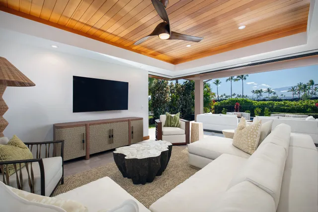 a living room with furniture a flat screen tv and a floor to ceiling window