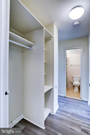 a view of a hallway with wooden floor and a bathroom