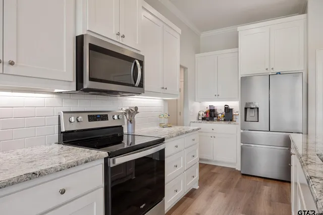 a kitchen with white cabinets and stainless steel appliances