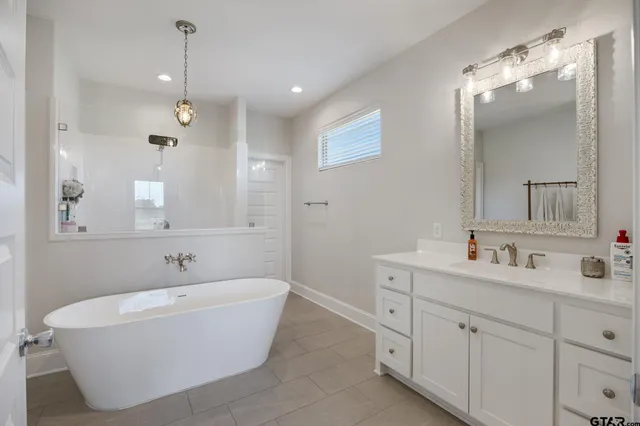 a bathroom with a white tub a double vanity sink and a mirror