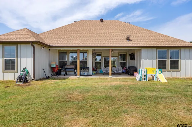 a view of a house with pool lawn chairs and a yard