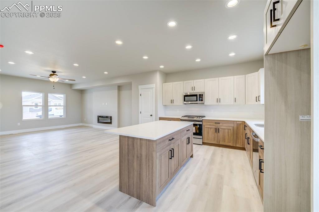 205 High Meadows Drive Florence, CO 81226 - Photo 3 of 28 a large kitchen with stainless steel appliances granite countertop a large center island a stove a refrigerator white cabinets and wooden floor