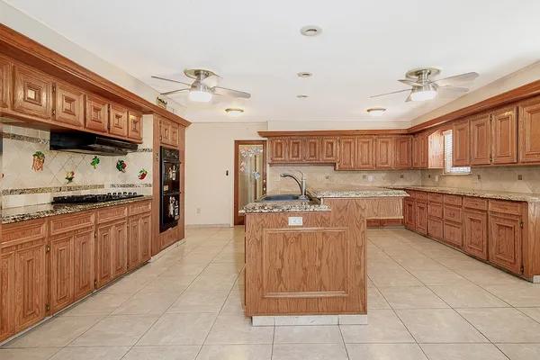 a large kitchen with kitchen island granite countertop a sink counter top space appliances and cabinets