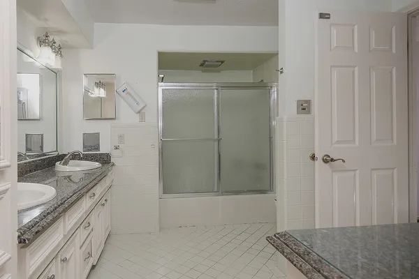 a spacious bathroom with a granite countertop sink a mirror and shower