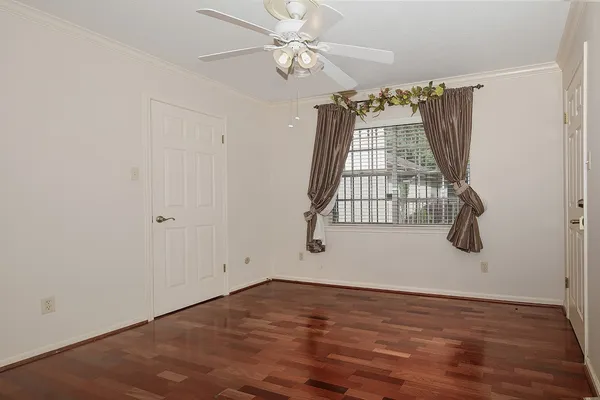 an empty room with wooden floor fan and windows