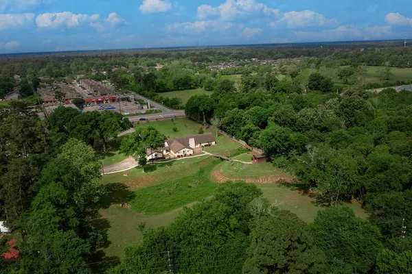 an aerial view of residential houses with outdoor space and trees