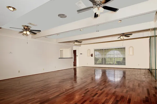 a view of an empty room with a window and wooden floor