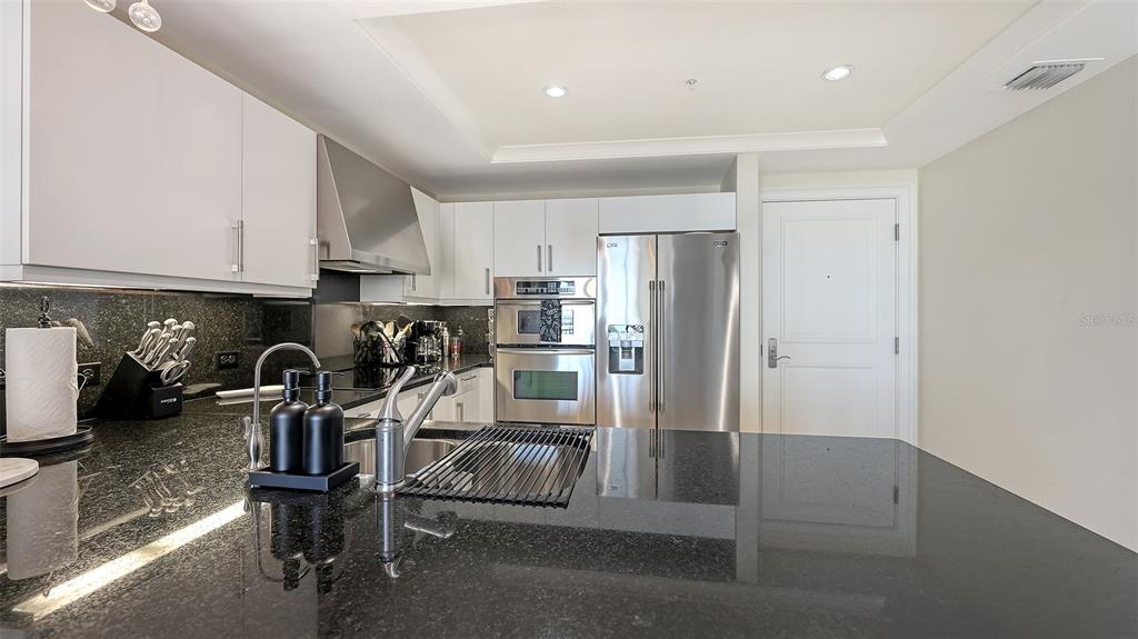 1350 Main Street, Unit 1007 Sarasota, FL 34236 - Photo 7 of 48 a kitchen with stainless steel appliances granite countertop a refrigerator and a stove top oven