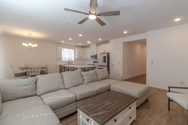 a kitchen with stainless steel appliances granite countertop a stove top oven a sink dishwasher a dining table and chairs with wooden floor