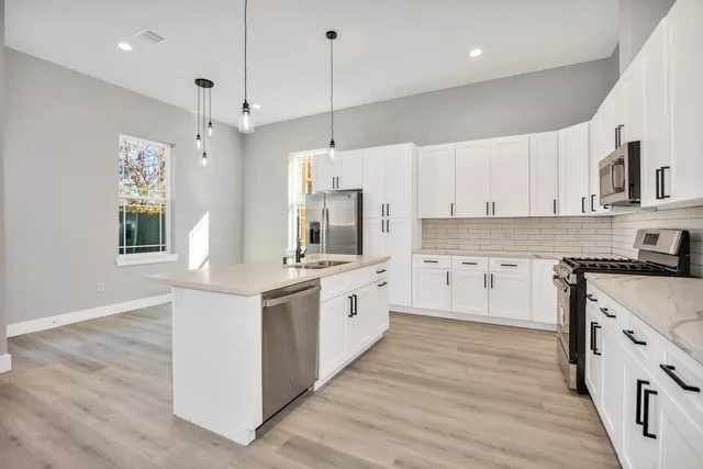 a large kitchen with stainless steel appliances granite countertop a stove a sink and a refrigerator