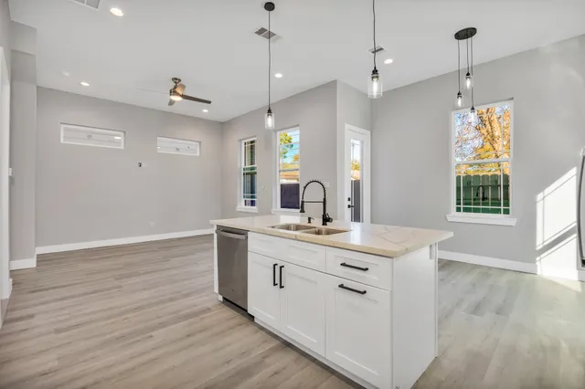 a view of a kitchen counter space a sink wooden floor and windows
