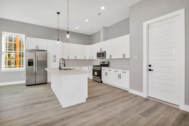 a kitchen with wooden floors and white cabinets