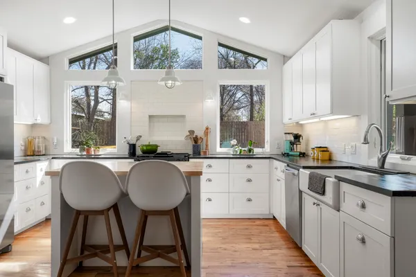 a kitchen with stainless steel appliances granite countertop a table chairs sink and cabinets