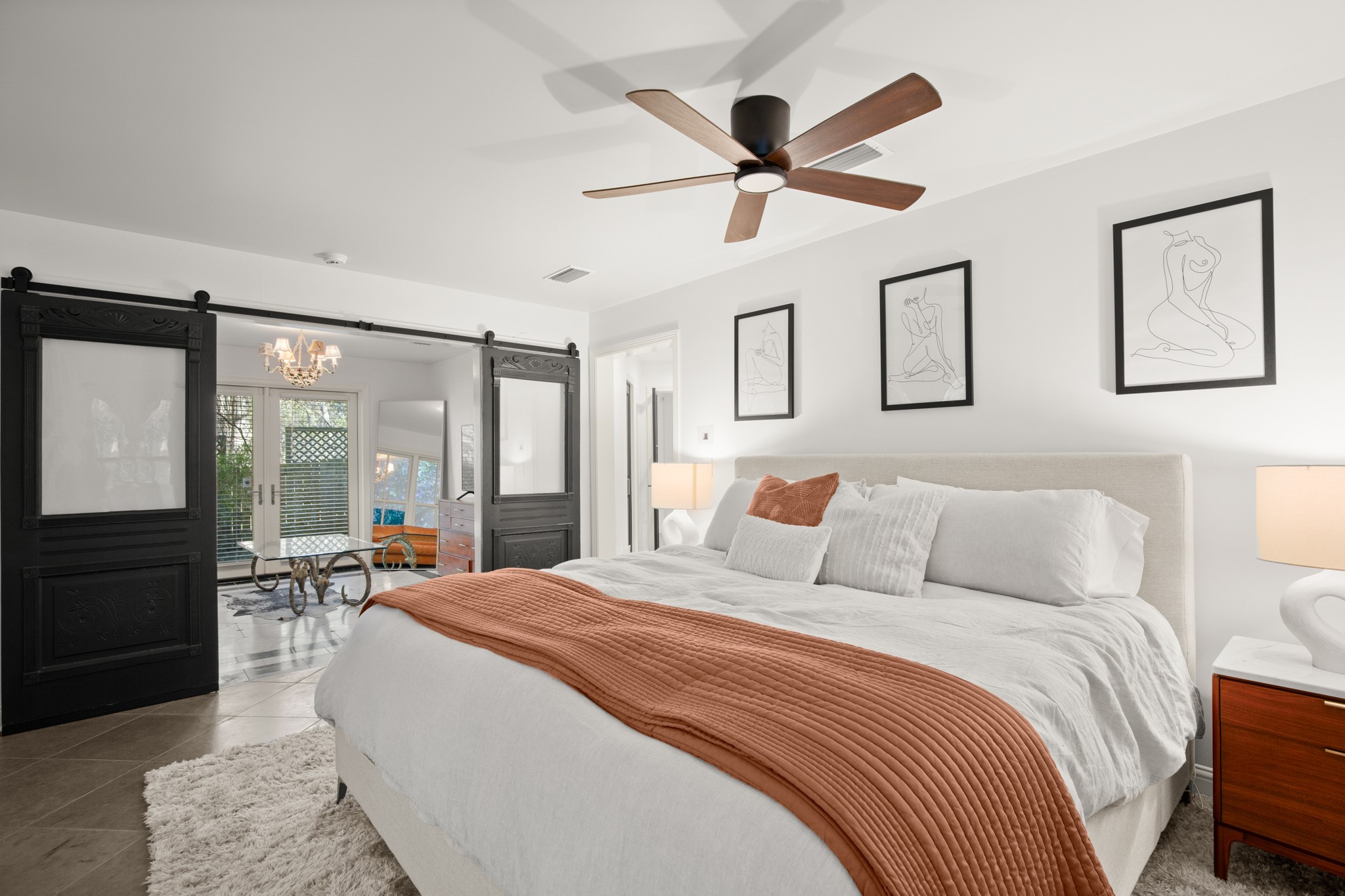 1601 Whitney Way Austin, TX 78741 - Photo 22 of 30 Sliding barn doors lead to an inviting sunroom, enhancing this bedroom's elegant and comfortable atmosphere.