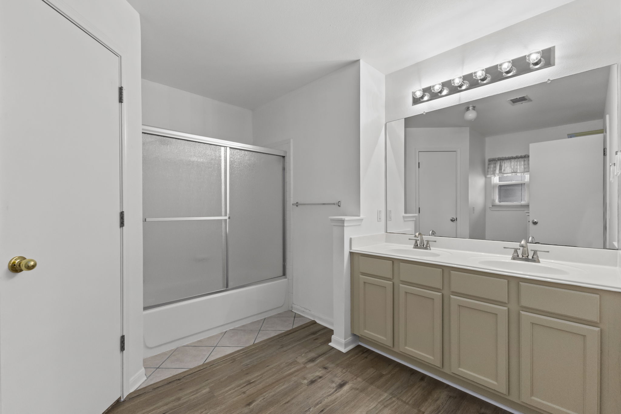 290 Bailey Loop Kyle, TX 78640 - Photo 21 of 33 Bathroom featuring a dual vanity with a white countertop and wood-finish cabinetry, a large mirror, and a tub/shower combination with sliding frosted glass doors